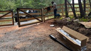 North Georgia Fence Company technician working on a Linear gate operator in Talking Rock, GA, with the gate system and replacement parts visible.